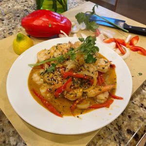 Plate of red chili garlic shrimp surrounded by peppers