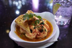 A bowl of red chili garlic shrimp with bread on top