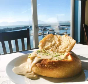 Clam chowder pouring out a fresh bun, with ocean views