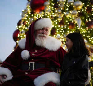 Santa Claus and a little girl in front of a Christmas tree